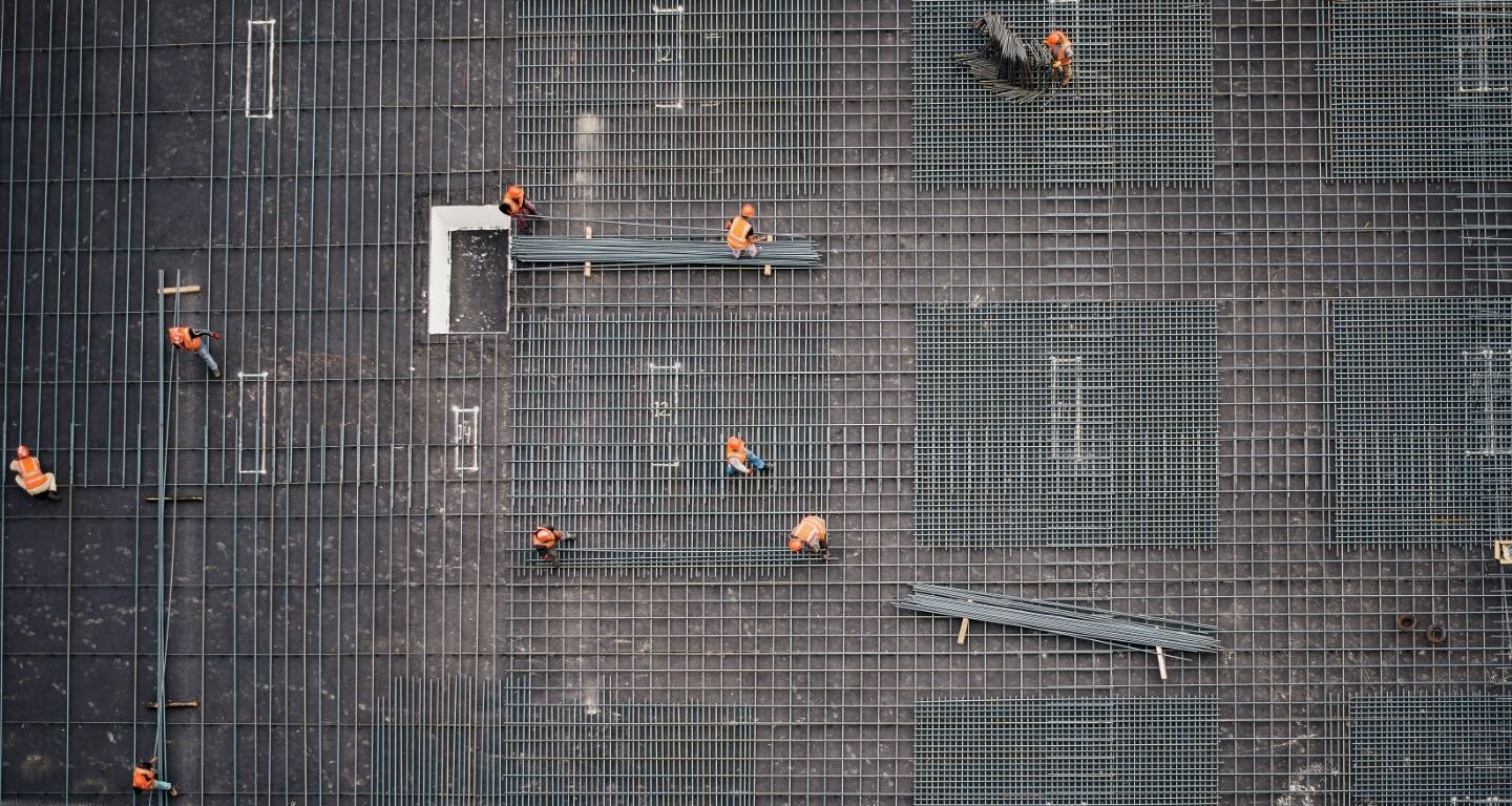 Over head shot of workers in orange vests working on rebar